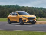 Ford Mustang Mach E GT geel zijkant aan het rijden op een racebaan