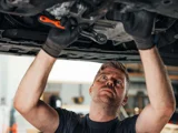 Van der Burgh monteur bezig onder een auto