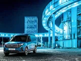 Ford E-Transit Courier blauw schuinvoorkant geparkeerd bij een blauw gebouw