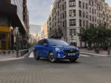 Ford Kuga 2023 blauw aan het rijden in een stad